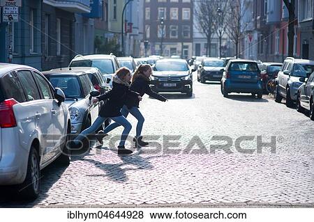 Stock Photo - Two teenagers running across a street, Düsseldorf, North Rhine-Westphalia, Germany, Europe. Fotosearch
