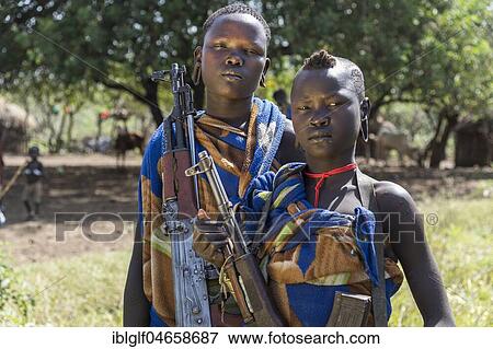 Two young women with Kalashnikovs, AK47, warrior, portrait, Mursi tribe, Southern Nations Nationalities and Peoples' Region, Ethiopia, Africa View Large Photo Image Stock Photo - Two young women with Kalashnikovs, AK47, warrior, portrait, Mursi tribe, Southern Nations Nationalities and Peoples' Region, Ethiopia, Africa. Fotosearch