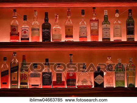 Stock Photography - Various whisky bottles on the shelf of a bar, illuminated red, North Rhine-Westphalia, Germany, Europe. Fotosearch
