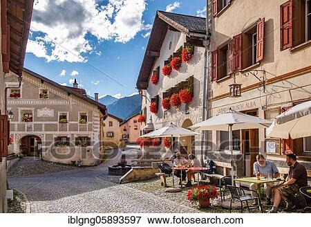 Stock Photo - Village street with restaurant terrace and typical houses, mountain village Guarda, Inn valley, Lower Engadine, Engadine, Grisons, Switzerland, Europe. Fotosearch