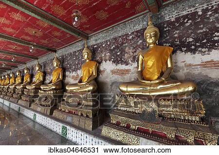 Stock Image - Wall with row of golden Buddha statues in meditation posture, on decorated pedestals, Phra Rabieng Kot, Wat Suhtat, royal temple, Phra Nakhon, Bangkok, Thailand, Asia. Fotosearch