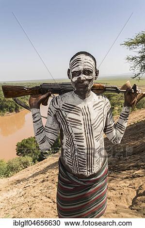 Stock Image - Warrior with rifle, Kalashnikov, AK47, Karo tribe, back Omo River, Southern Nations Nationalities and Peoples' Region, Ethiopia, Africa. Fotosearch