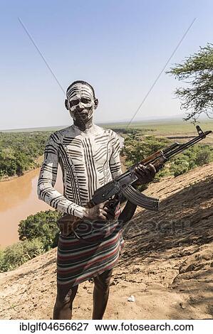 Warrior with rifle, Kalashnikov, AK47, Karo tribe, back Grandma River, Southern Nations Nationalities and Peoples' Region, Ethiopia, Africa View Large Photo Image Stock Photo - Warrior with rifle, Kalashnikov, AK47, Karo tribe, back Grandma River, Southern Nations Nationalities and Peoples' Region, Ethiopia, Africa. Fotosearch