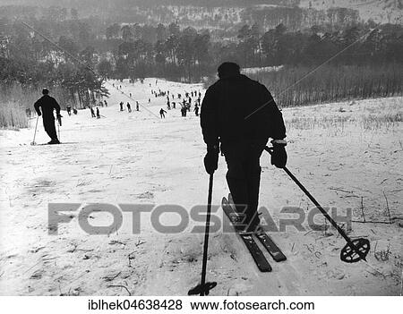 Winter sports, man drives down the slope and looks into a valley full of skiers, 1920s, exact place unknown, Germany, Europe View Large Photo Image Stock Photo - Winter sports, man drives down the slope and looks into a valley full of skiers, 1920s, exact place unknown, Germany, Europe. Fotosearch