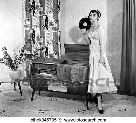 Stock Photo - Woman in front of a record player in the living room, 1950s, Germany, Europe. Fotosearch