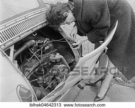 Stock Image - Woman repairing a car, 1960s, Germany, Europe. Fotosearch