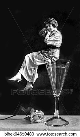 Stock Image - Woman sitting on a champagne glass, New Year, New Year's Eve, 1920s, Germany, Europe. Fotosearch