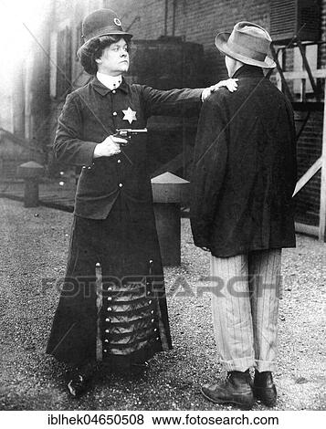 Stock Photo - Woman with a gun and disguised as a policewoman arrests a man, 1920s, Germany, Europe. Fotosearch