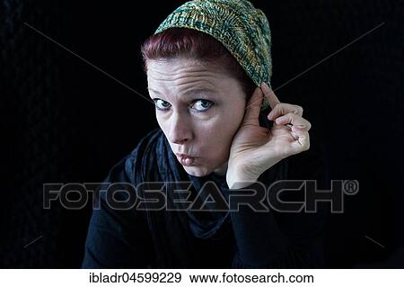 Stock Photo - Woman with green wool hat, looks playful, against a black background. Fotosearch