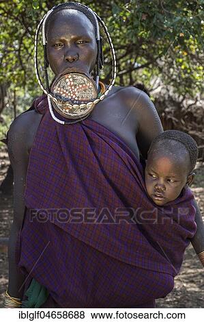 Stock Photo - Woman with lip plate and headdress with baby, portrait, tribe of the Mursi, Southern Nations Nationalities and Peoples' Region, Ethiopia, Africa. Fotosearch