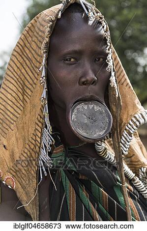 Stock Image - Woman with lip plates and headdress, portrait, tribe of the Mursi, Southern Nations Nationalities and Peoples' Region, Ethiopia, Africa. Fotosearch