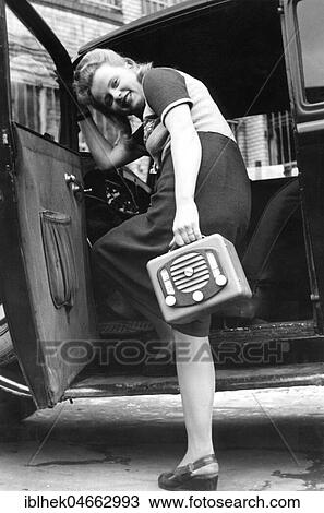Stock Image - Woman with radio gets into a car, 1940s, Germany, Europe. Fotosearch