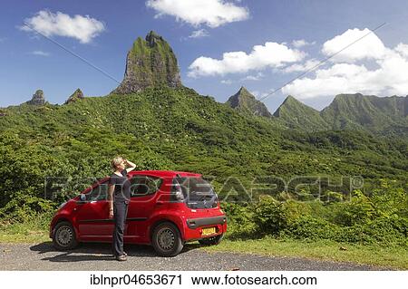 Woman with red car at Belvedere vantage point, green mountain range with green vegetation and highest peaks, Mont Tohiea, 1207 m, Moorea, Society Islands, Windward Islands, French Polynesia, Oceania View Large Photo Image Stock Image - Woman with red car at Belvedere vantage point, green mountain range with green vegetation and highest peaks, Mont Tohiea, 1207 m, Moorea, Society Islands, Windward Islands, French Polynesia, Oceania. Fotosearch