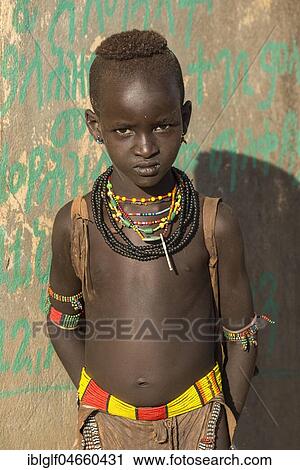 Stock Image - Young boy, approx. 9 years old, posing with a serious glance in front of a colourful wall, Hamer tribe, Turmi market, Southern Nations Nationalities and Peoples' Region, Ethiopia, Africa. Fotosearch