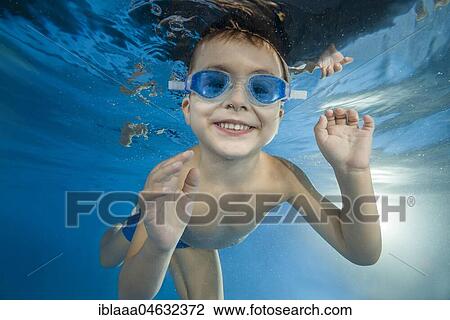 Young boy wearing swimming goggles dives in a pool View Large Photo Image Stock Image - Young boy wearing swimming goggles dives in a pool. Fotosearch
