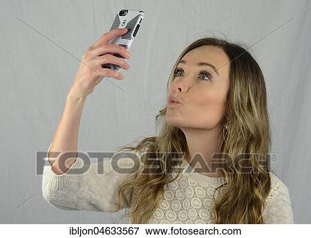 Young woman make a selfie with a mobil phone, kissing lips View Large Photo Image Stock Photo - Young woman make a selfie with a mobil phone, kissing lips. Fotosearch