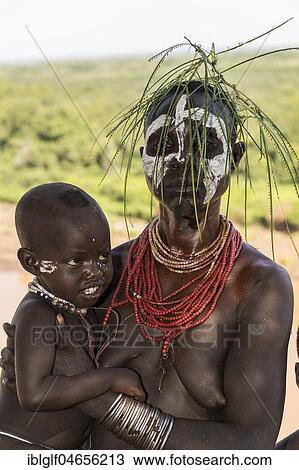 Stock Image - Young woman with toddler, with head and necklaces, Karo tribe, Omo River, Southern Nations Nationalities and Peoples' Region, Ethiopia, Africa. Fotosearch