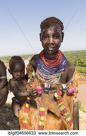 Stock Image - Young women with face painting and baby, Karo tribe, behind Omo River, Southern Nations Nationalities and Peoples' Region, Ethiopia, Africa. Fotosearch