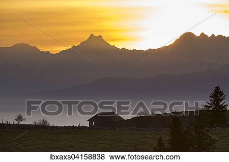 Stock Photo - Eine Hutte am Creux du Van bei Sonnenaufgang mit Ausblick auf das Schreckhorn, 4078 m, Lauteraarhorn, 4042 m, Eiger, 3970 m, Finsteraarhorn, 4274 m, und Grosses Fiescherhorn, 4048 m, Gorgier, Neuenburg, Schweiz, Europa. Fotosearch