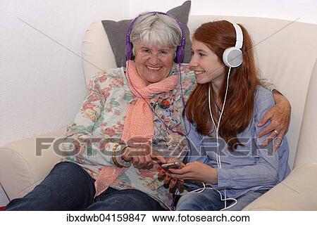 Enkelin und Grossmutter horen Musik uber Kopfhorer, digitale Musik, Bayern, Deutschland, Europa View Large Photo Image Stock Photo - Enkelin und Grossmutter horen Musik uber Kopfhorer, digitale Musik, Bayern, Deutschland, Europa. Fotosearch