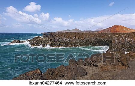 Picture - Felskuste von Los Hervideros, Vulkanlandschaft, hinten Feuerberge im Timanfaya Nationalpark, Lanzarote, Kanarische Inseln, Spanien, Europa. Fotosearch