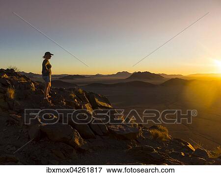 Frau bei Sonnenuntergang mit Ausblick auf Tsarisberge, Region Hardap, Namibia, Afrika View Large Photo Image Stock Photo - Frau bei Sonnenuntergang mit Ausblick auf Tsarisberge, Region Hardap, Namibia, Afrika. Fotosearch