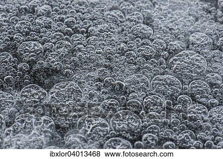 Stock Photo - Gefrorene Luftblasen in weissem Eis. Fotosearch