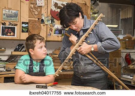 Stock Photography - Junge Bauerin repariert Heurechen, Stiel einbauen, Sohn schaut zu, Bauernhof der Familie Sprenger, Schwaz, Tirol, Osterreich, Europa. Fotosearch