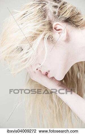 Junge Frau mit langen blonden Haaren, Blick nach unten, Hand am Gesicht View Large Photo Image Stock Image - Junge Frau mit langen blonden Haaren, Blick nach unten, Hand am Gesicht. Fotosearch
