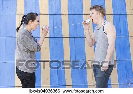 Junge Frau und junger Mann mit einem Dosentelefon, beide schreien in eine Blechdose hinein, Symbolbild, Kommunikation in einer Beziehung View Large Photo Image Stock Photograph - Junge Frau und junger Mann mit einem Dosentelefon, beide schreien in eine Blechdose hinein, Symbolbild, Kommunikation in einer Beziehung. Fotosearch