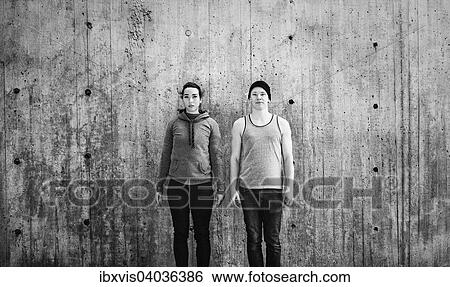 Junge Frau und junger Mann stehen vor Betonwand, Schweden, Europa View Large Photo Image Stock Photograph - Junge Frau und junger Mann stehen vor Betonwand, Schweden, Europa. Fotosearch