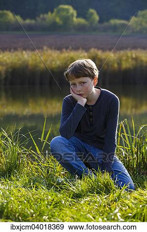 Stock Photo - Junge sitzt traurig an einem kleinen See, Wandersleben, Thuringen, Deutschland, Europa. Fotosearch