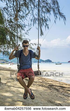 Stock Photograph - Junger Mann auf einer Schaukel, Sandstrand, turkises Meer, Sairee Beach, Insel Koh Tao, Golf von Thailand, Thailand, Asien. Fotosearch