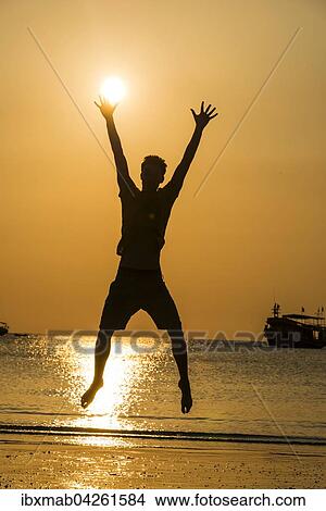 Picture - Junger Mann, Silhouette, springt am Strand bei Sonnenuntergang, Abendrot am Meer, Koh Tao, Thailand, Asien. Fotosearch