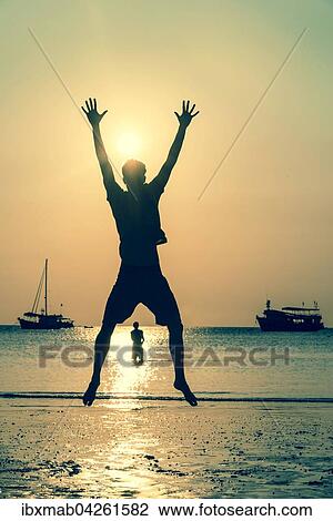 Stock Image - Junger Mann, Silhouette, springt am Strand bei Sonnenuntergang, Abendrot am Meer, Koh Tao, Thailand, Asien. Fotosearch