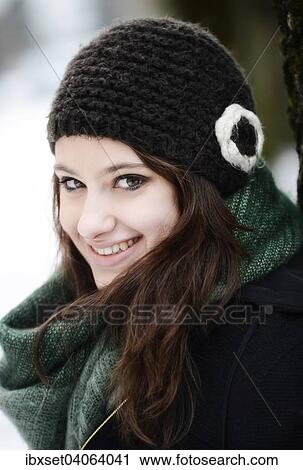 Stock Image - Lachelnde junge Frau mit Mutze und Schal im Winter, Portrait. Fotosearch