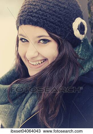 Stock Image - Lachelnde junge Frau mit Mutze und Schal im Winter, Portrait. Fotosearch