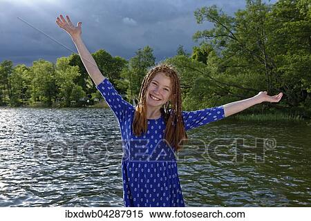 Stock Photography - Madchen auf einem Steg vor dunklen Wolken am Ellbogensee, Mecklenburgische Seenplatte, Mecklenburg-Vorpommern, Deutschland, Europa. Fotosearch