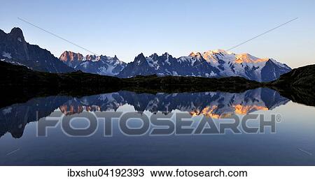 Stock Image - Mont Blanc Massiv bei Sonnenaufgang spiegelt sich im Lac de Chesserys, links Aiguilles de Chamonix, rechts Mont Blanc, Chamonix, Frankreich, Europa. Fotosearch