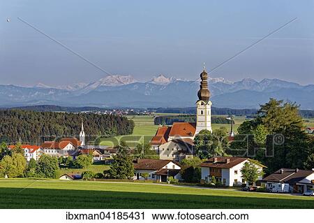 Stock Image - Ortsansicht mit Pfarrkirche Maria Himmelfahrt, hinten die Berchtesgadener Alpen mit Watzmann, Schnaitsee, Chiemgau, Oberbayern, Bayern, Deutschland, Europa. Fotosearch