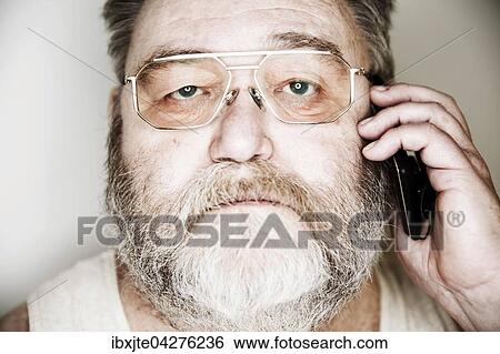 Stock Photograph - Senior mit Vollbart und Brille im Unterhemd telefoniert mit einem Smartphone, Portrait, Deutschland, Europa. Fotosearch