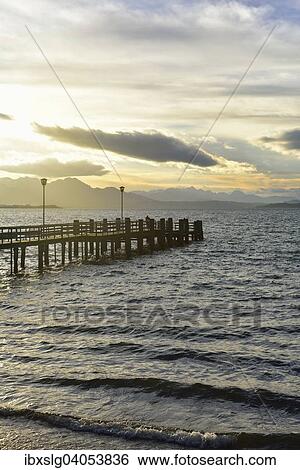 Steg bei Sonnenuntergang am Chiemsee, Silhouette Chiemgauer und Schlierseer Alpen, bei Chieming, Chiemgau, Alpenvorland, Bayern, Deutschland, Europa View Large Photo Image Stock Photograph - Steg bei Sonnenuntergang am Chiemsee, Silhouette Chiemgauer und Schlierseer Alpen, bei Chieming, Chiemgau, Alpenvorland, Bayern, Deutschland, Europa. Fotosearch
