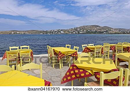 Stock Image - Tische und Stuhle in einem Restaurant am Meer, Parikia, Paros, Kykladen, Griechenland, Europa. Fotosearch