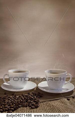 Zwei Tassen dampfender Kaffee, davor Kaffeebohnen View Large Photo Image Stock Photograph - Zwei Tassen dampfender Kaffee, davor Kaffeebohnen. Fotosearch