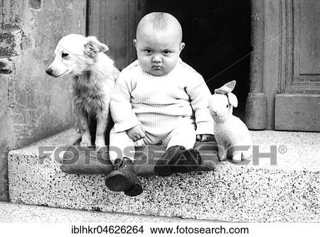 Picture - A baby with a dog and plush rabbit sits on a landing and looks grimly into the camera. Fotosearch