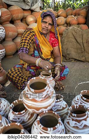 Stock Image - A woman painting pots and water jugs at a pottery stall in Jaipur, Rajasthan, India, Asia. Fotosearch
