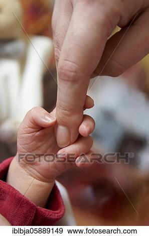 Stock Photo - Baby holding a mother's finger, France, Europe. Fotosearch