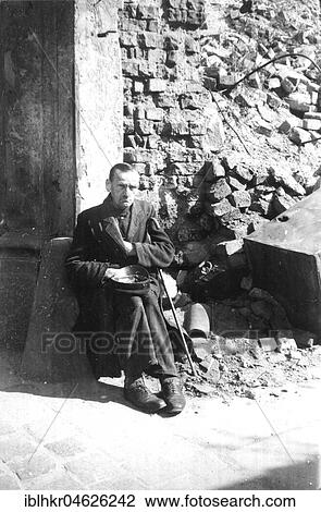 Stock Image - Beggar sitting in front of rubble, ca. 1945 Leipzig, Germany, Europe. Fotosearch