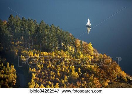 Biggest lake, shore of the lake with autumnal deciduous forest and a sail boat, Attendorn, Sauerland, North Rhine-Westphalia, Germany, Europe View Large Photo Image Stock Photo - Biggest lake, shore of the lake with autumnal deciduous forest and a sail boat, Attendorn, Sauerland, North Rhine-Westphalia, Germany, Europe. Fotosearch
