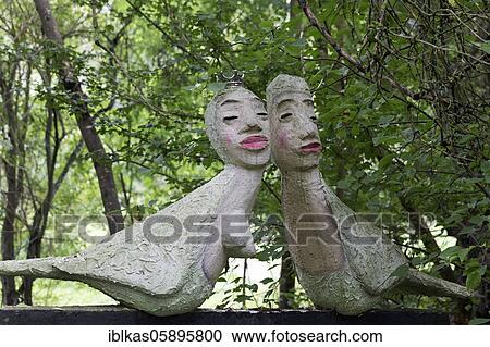 Stock Image - Bizarre pair of birds with human heads, figures in the sculpture garden of the artist Jochen Bach, Plinzmühle, Plinz, Großkröbitz, Milda, Thuringia, Germany, Europe. Fotosearch